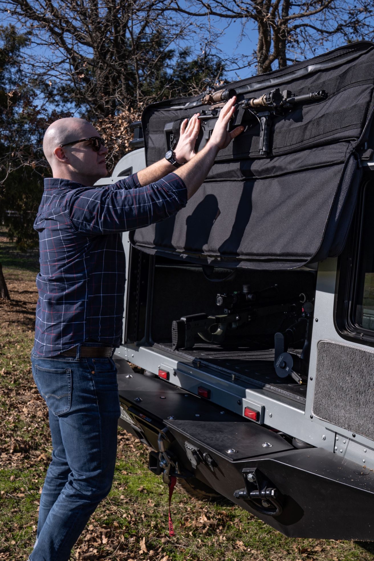 Man getting rifle out of black Single Rifle Case attached to back of vehicle.